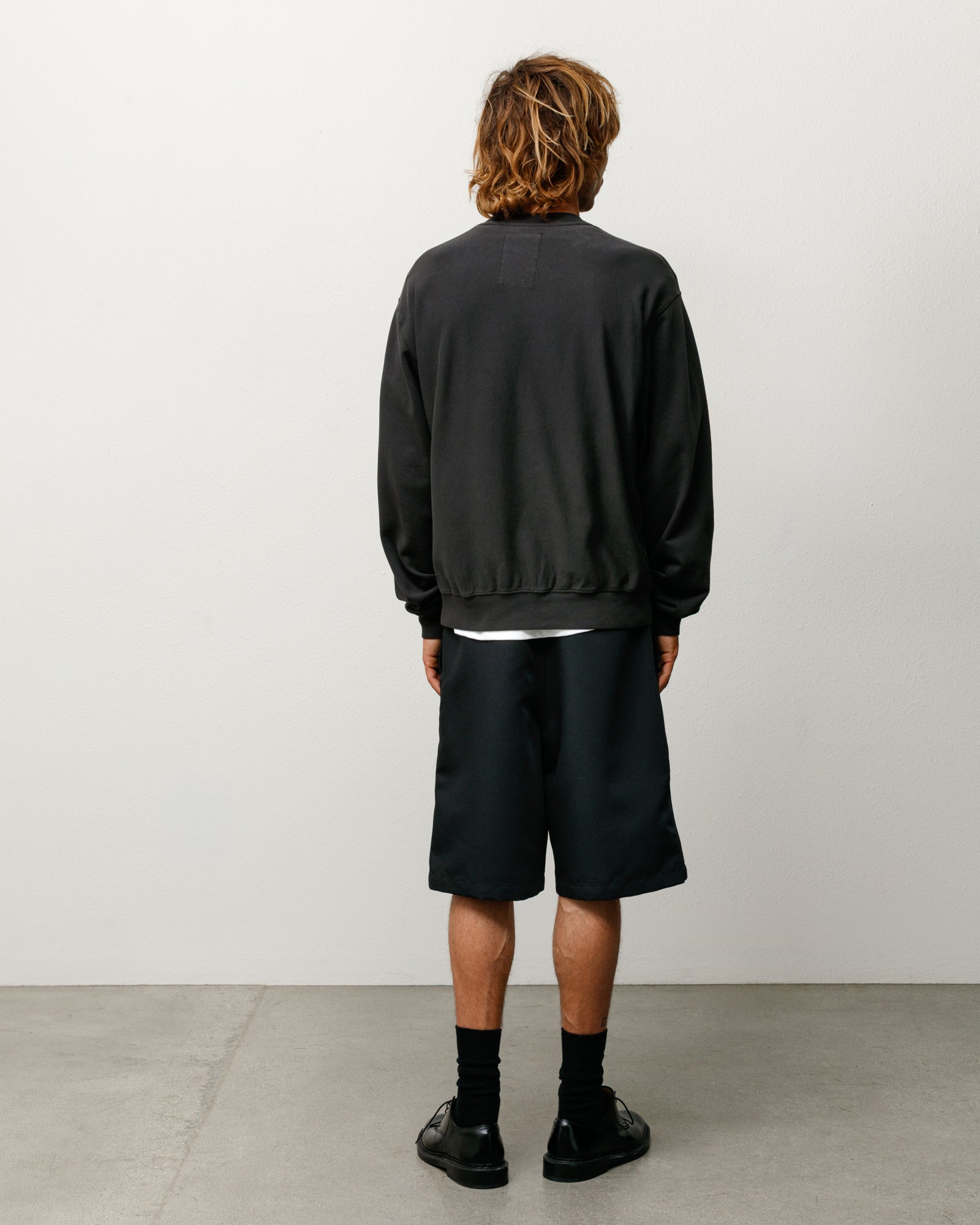 Baggy Beach Short in Black, back view on model with relaxed knee-length fit