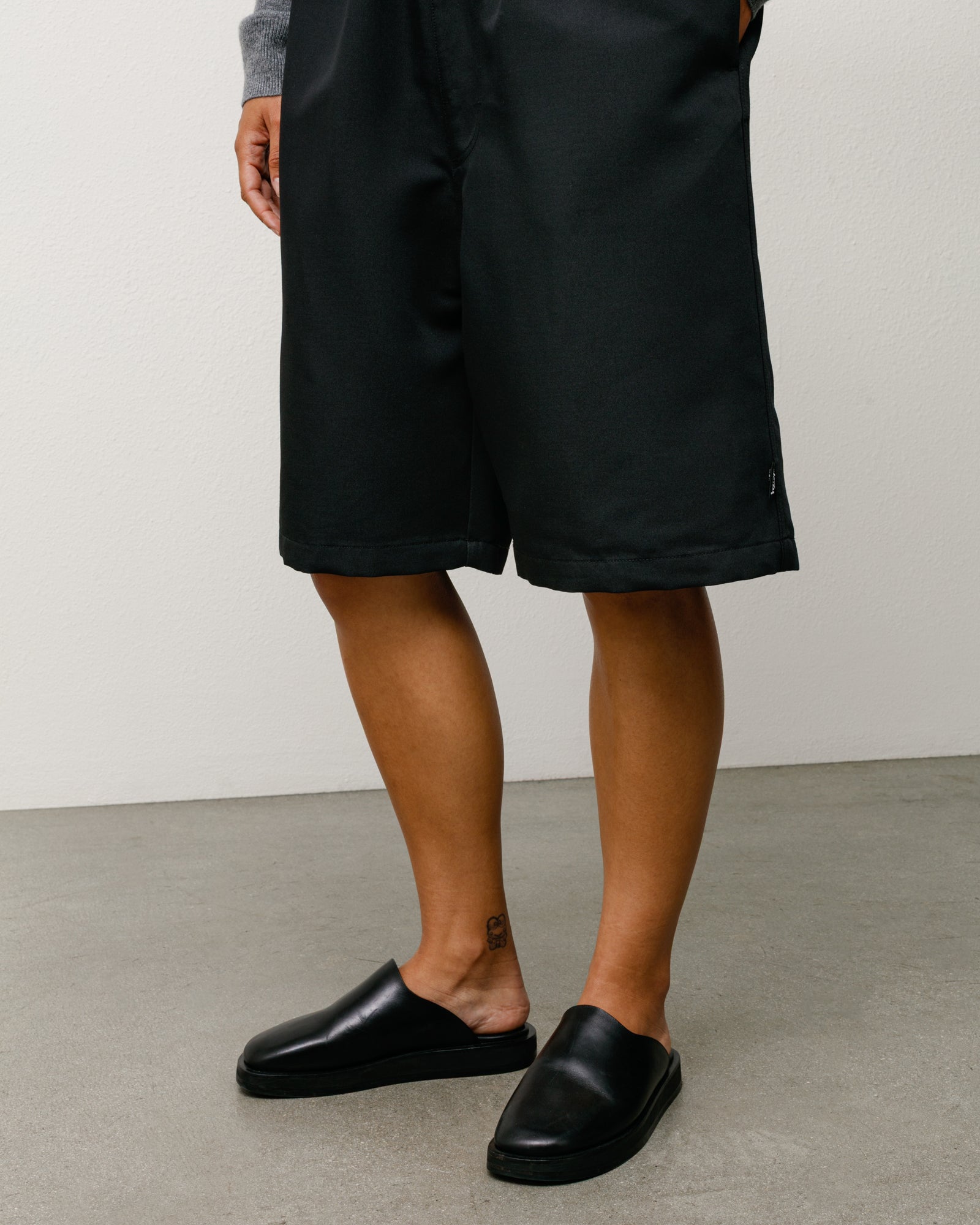 Baggy Beach Short in Black, relaxed knee-length fit on model with clean hem and subtle side tag.