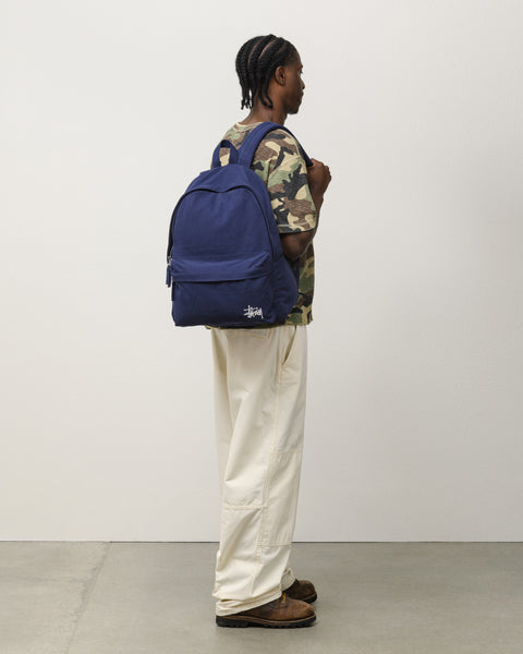 CANVAS BACKPACK Accessories in navy cotton canvas with white Stüssy logo, on-body side view.