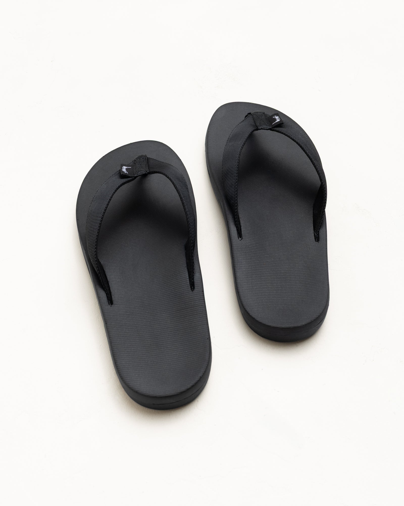 Unisex black rubber flip-flops with nylon webbing straps, top view on white background
