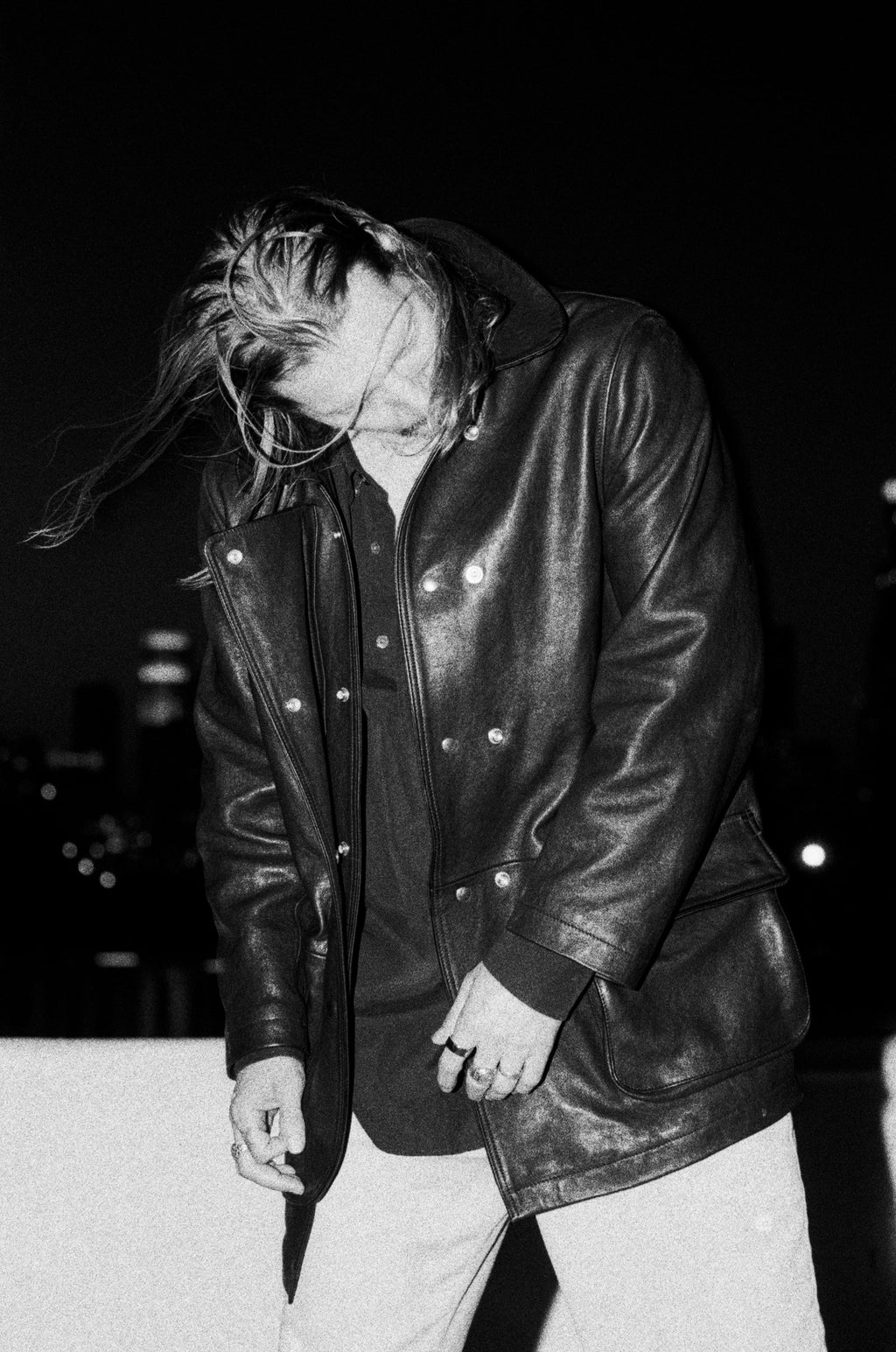 Black and white photo of a model with long hair wearing the Our Legacy Leather Fireman Jacket.